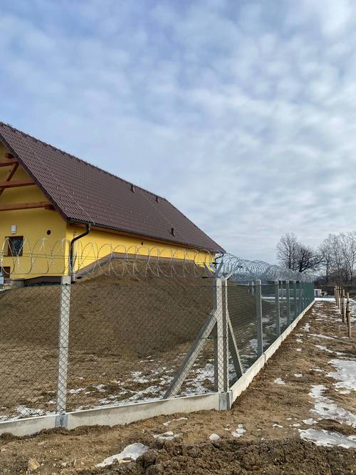Pletivový plot na betonových sloupcích se žiletkovým drátem kolem areálu