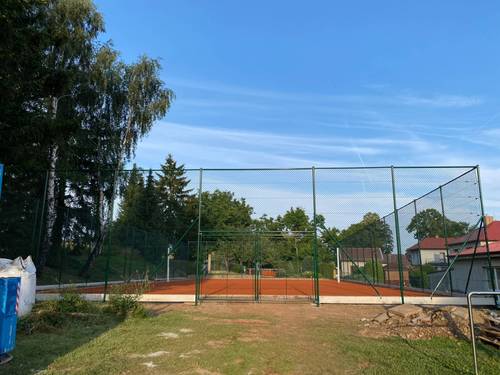 Zelené oplocení sportovního kurtu s bránou do areálu